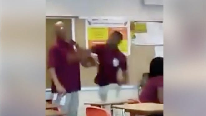 This screenshot of a video shows a South Division High School teacher being punched multiple times by a student.
