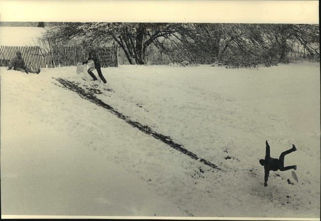 1987. Young man went flying as he and others used plastic baskets and sheets of cardboard to slide over a snow jump they made in Juneau Park.