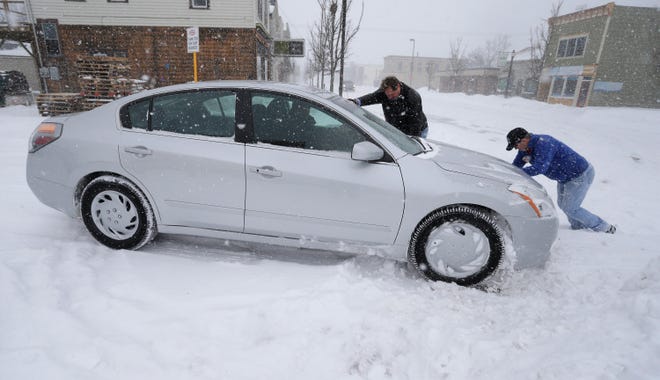 Trilling True Value's Greg Parmly, left, and Chris Schramm, help push a customer's car out of a snow bank, Monday, Jan. 28, 2019, in Sheboygan, Wis. Parmly said that his firm sold 15 snowblowers last week in anticipation of the storm.