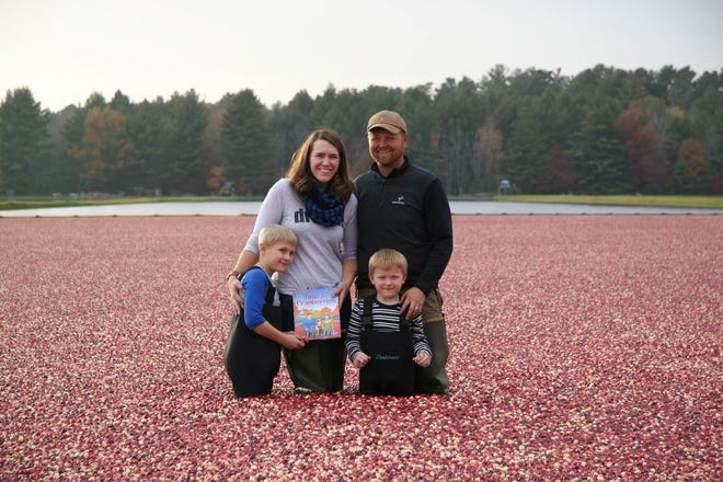 The Detlefsen family poses in 2015 with Lisl's first published book, Time for Cranberries while standing in a flooded bog at their farm family-owned cranberry marsh near Wisconsin Rapids.