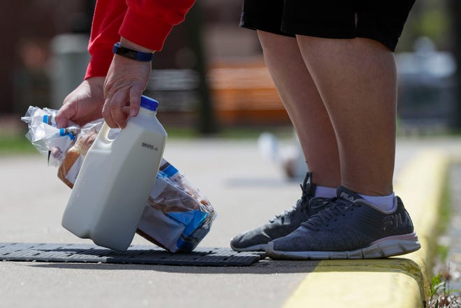 A parent picks up milk and bread from the curb on Thursday, May 7, 2020, at Wisconsin Rapids Lincoln High School in Wisconsin Rapids, Wis. Nurses from Aspirus donated and distributed 400 half gallons of milk and 400 loaves of bread in addition to free meals for children under 18.
Tork Mason/USA TODAY NETWORK-Wisconsin