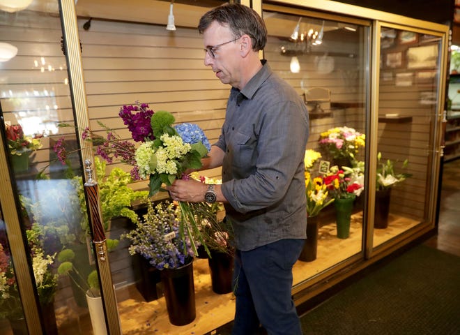 Phil Krainz, co-owner of Rose's Flower Shop, prepares a flower arrangement for an order at the reopened shop in Wauwatosa on Tuesday.