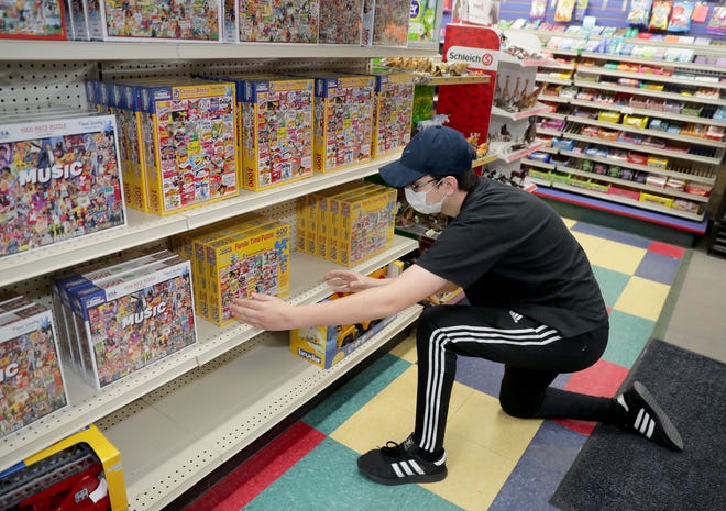 Employee Jack Stuhlmacher adjusts some puzzles on a shelf at Winkie's Toys & Variety in Whitefish Bay on Tuesday, May 12, 2020.   As of May 11, standalone or strip mall-based retail stores can offer in-person shopping, as long as customers are limited to five at a time and social-distancing guidelines are followed, Gov. Tony Evers announced Monday.