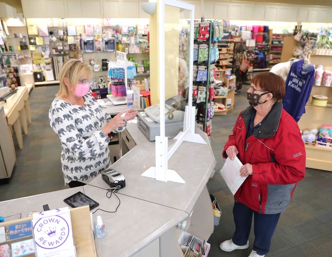 Julie Stuhmacher, left, co-owner of Winkie's, applies hand sanitizer after checking out customer Janice Kocinski at Winkie's Hallmark and Gifts in Whitefish Bay on Tuesday, May 12, 2020.
