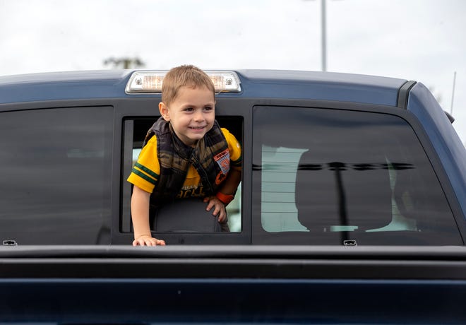 Josh Groshek, 3, climbs through the back window a truck.