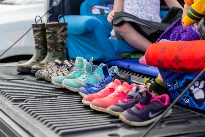 Shoes of children are lined on the bed of a pickup truck.