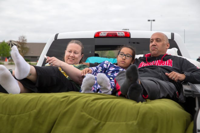 Khris Monteen, from left, Isabella Monteen, 10, and Rick Monteen lay in bed of a pickup truck waiting for the movies. The Monteen family drove from Waukesha.