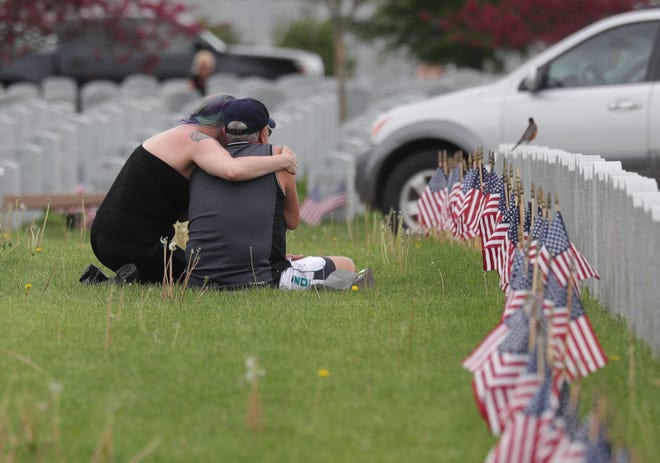 Katherine Corcoran, left, of Muskego comforts John Dutze of Anna, Texas, who was visiting the grave of his father, Harold Dutze, who served in the Navy, on Memorial Day at Southern Wisconsin Veterans Memorial Cemetery in Union Grove.