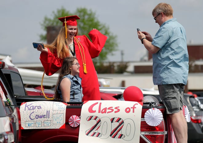 Kara Cowell has a picture taken with her sister Avery by their father Brian Cowell at the start of the Neenah High School class of 2020 graduation procession Wednesday, May 27, 2020, in Neenah, Wis. The Neenah Police Department helped honor seniors with the procession through the city before their virtual ceremony scheduled later in the evening.