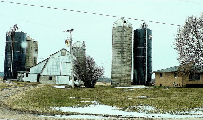 A farm with a solid concrete, two concrete stave and two Harvestores that cover over a 100 year period of silo types.